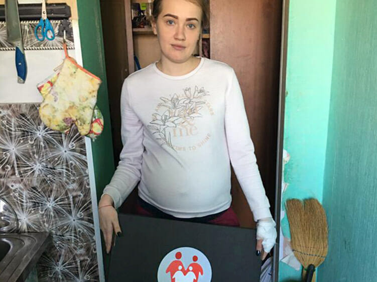 A woman holding a box in her kitchen.