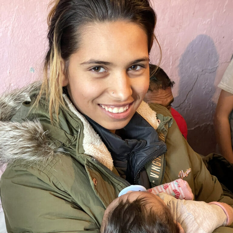 A woman holding a baby in front of a group of people.