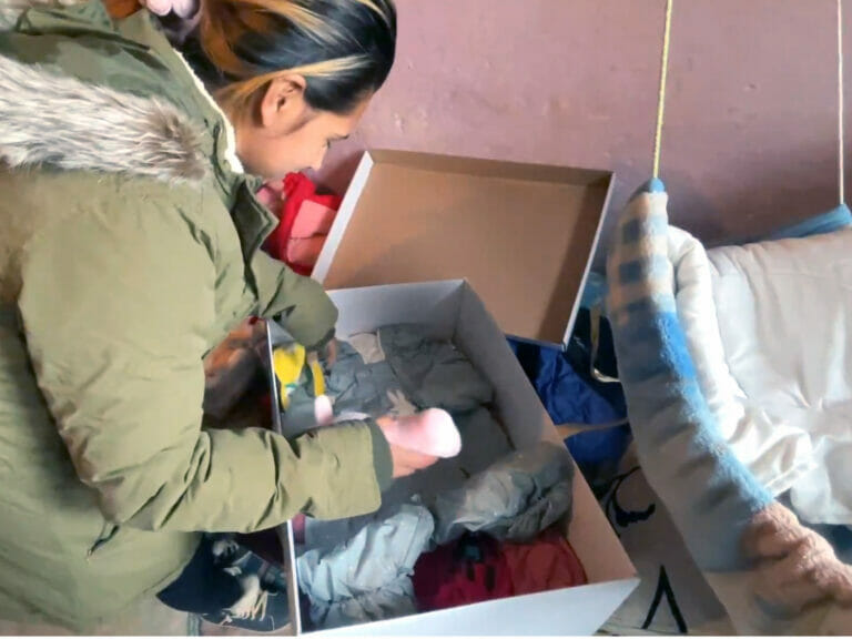 A woman is putting clothes into a box.