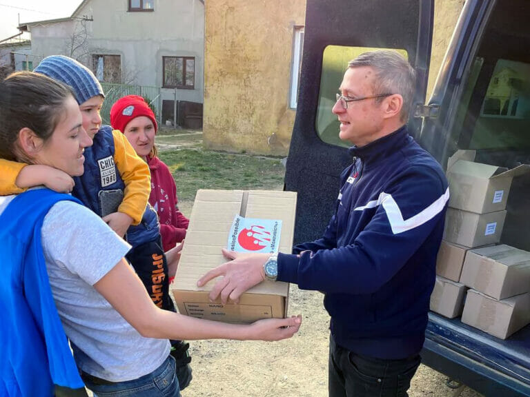 A man is handing out boxes to a group of children.