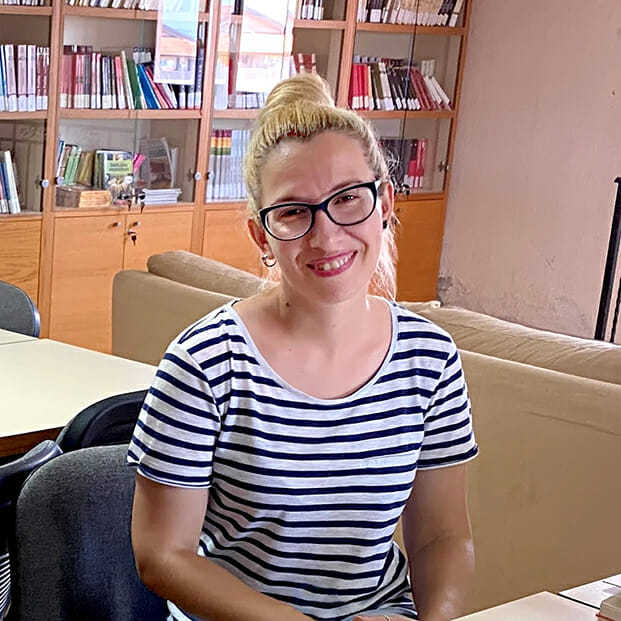 A woman sitting at a table with books in front of her.