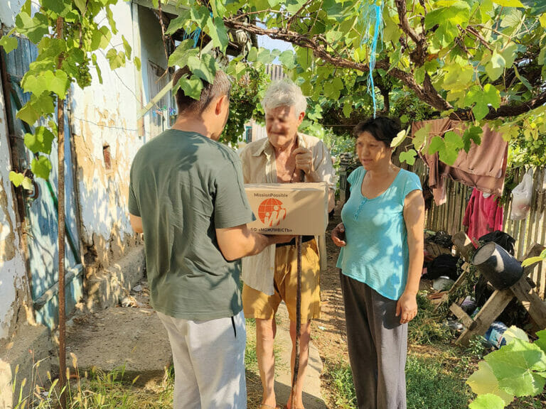 A group of people standing under a tree with a box.