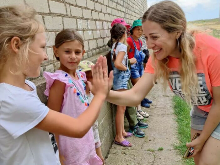 A woman giving a high five to a group of children.