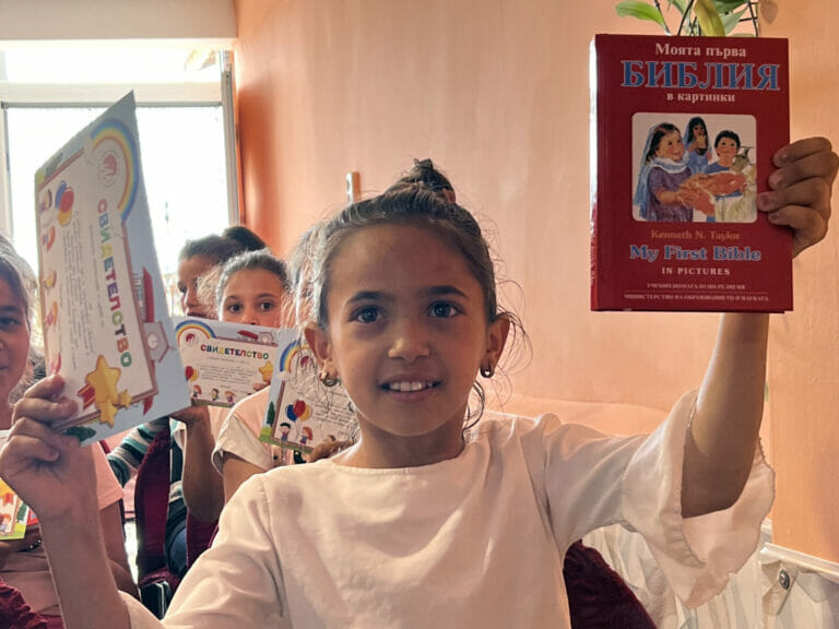 A girl is holding up a book in front of a group of people.