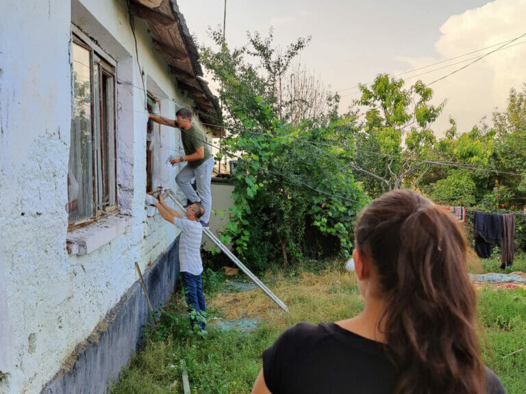 A group of people working on a house in a yard.