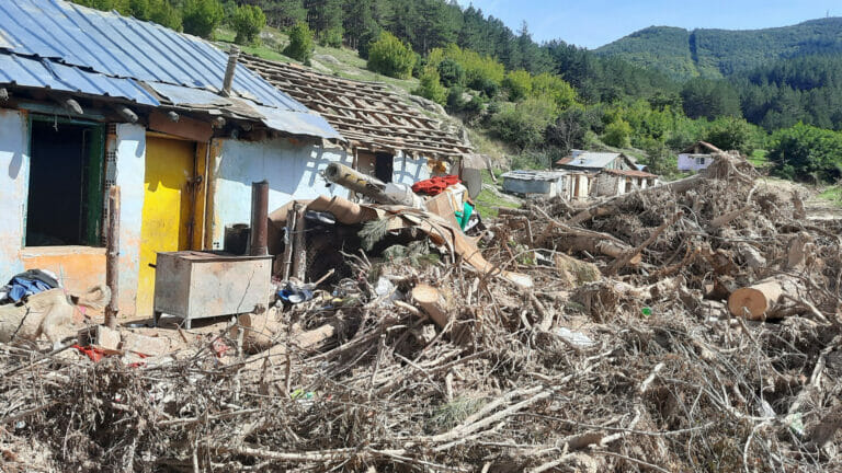 A man stands determinedly in front of a house that has fallen down, making it his mission to rebuild.