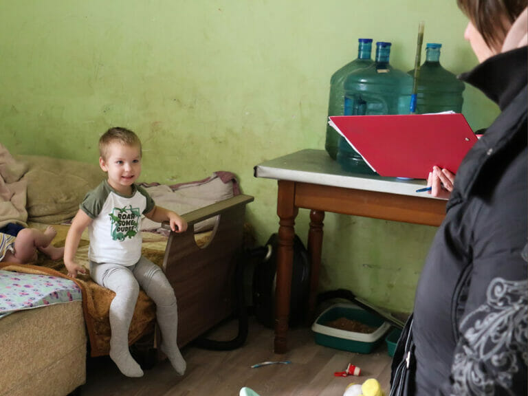 A woman is on a mission talking to a child in a room.
