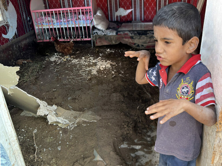 A boy is on a mission with a chicken in a room.