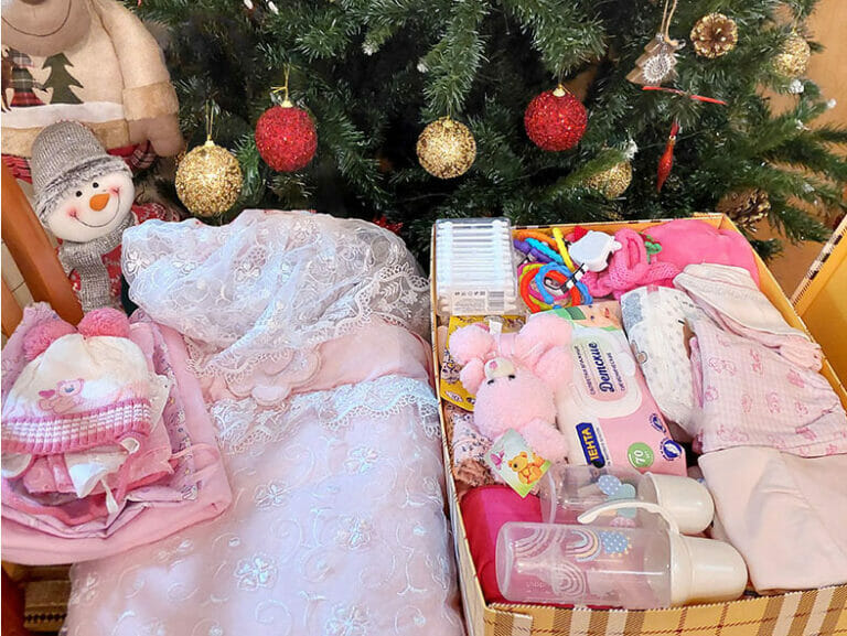 A basket of baby items next to a Christmas tree on a mission.
