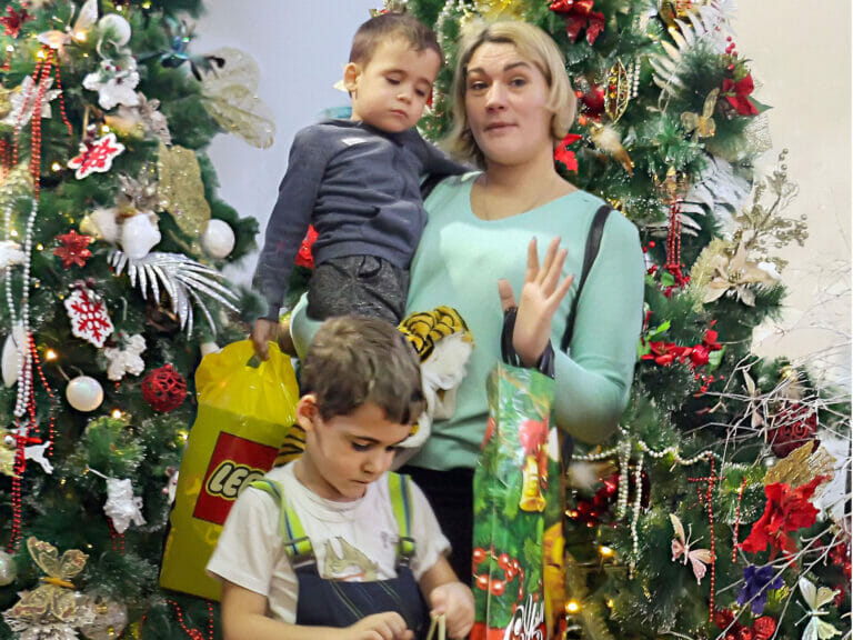 A woman and two children posing in front of a Christmas tree.
