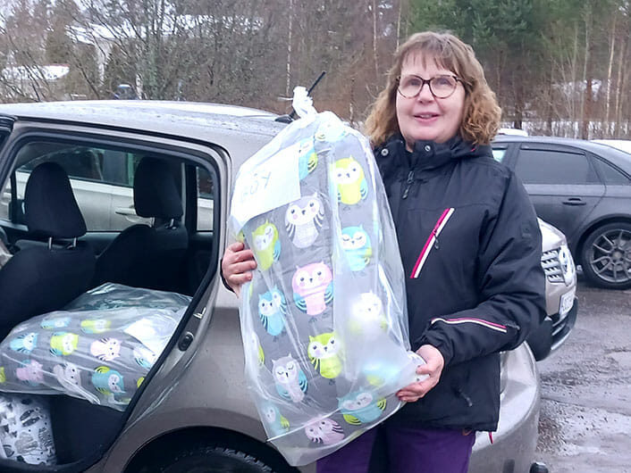 A woman undertaking a Mission Possible with a bag in front of her car.