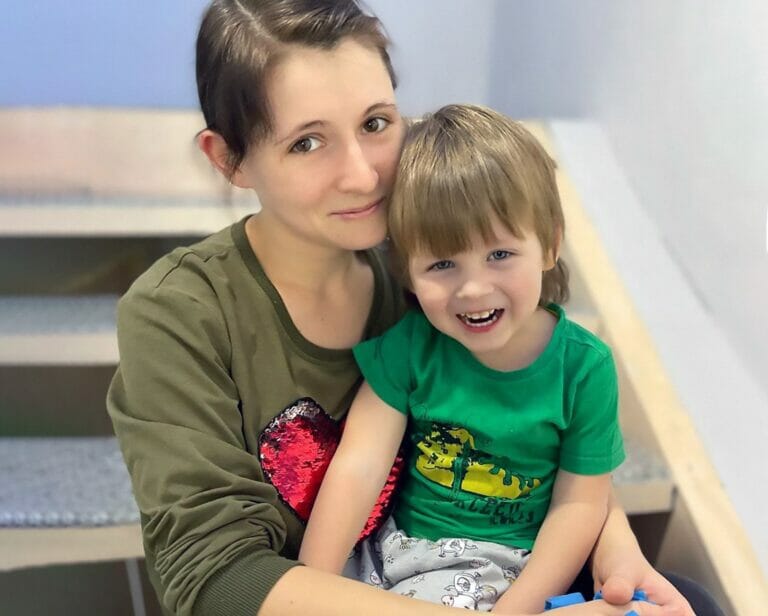 A woman holding a child on a set of stairs, embarking on a Mission Possible.