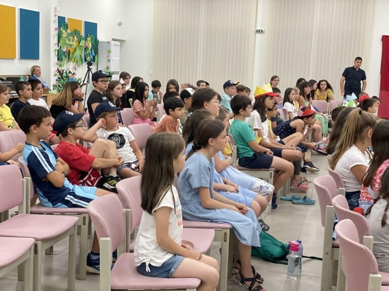 A group of children are sitting in chairs in a classroom.