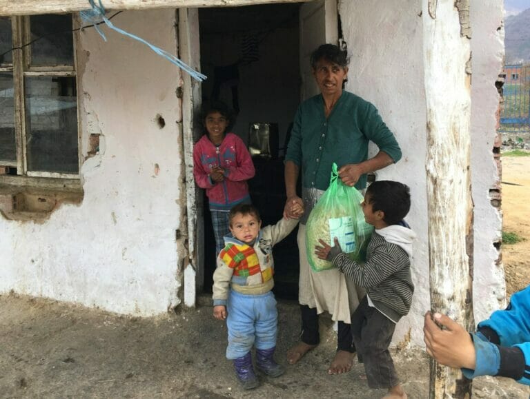 A woman and two children standing in front of a house.