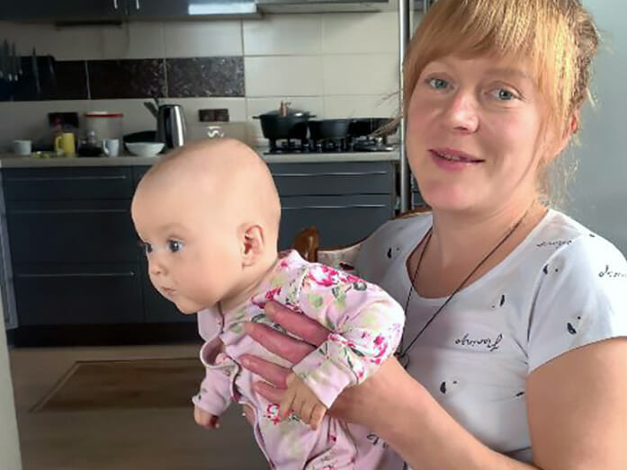 A woman holding a baby in a kitchen.