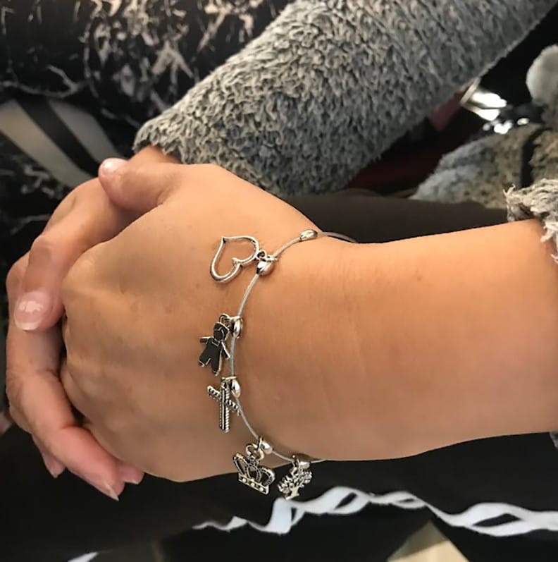 A woman's hand holding a bracelet with charms on it.